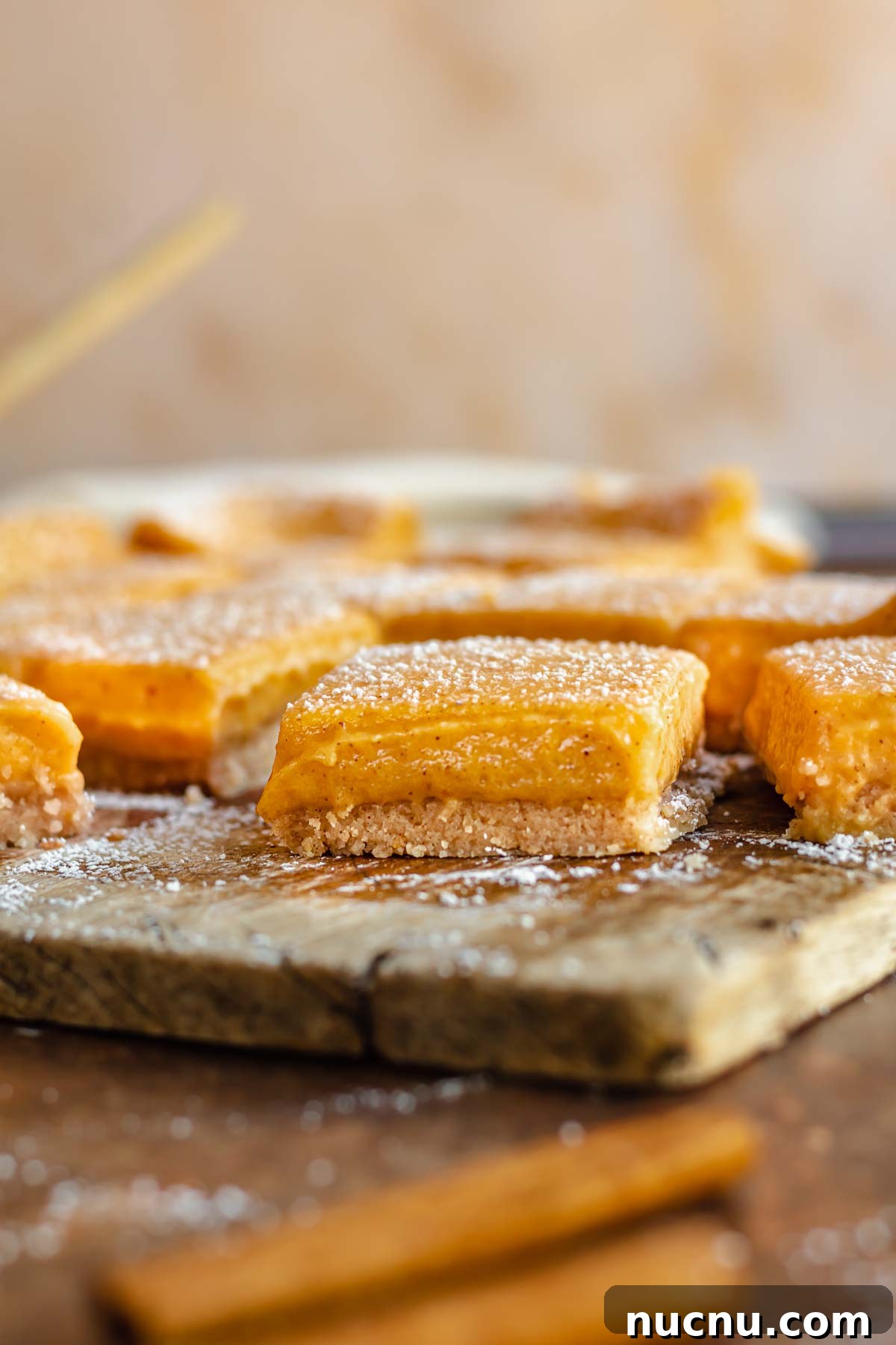 Cut pumpkin bars on a cutting board. One has a bite removed.
