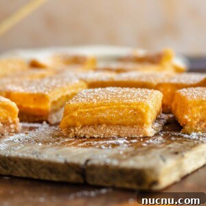 Pumpkin gooey bars on a cutting board cut apart and dusted with powdered sugar.