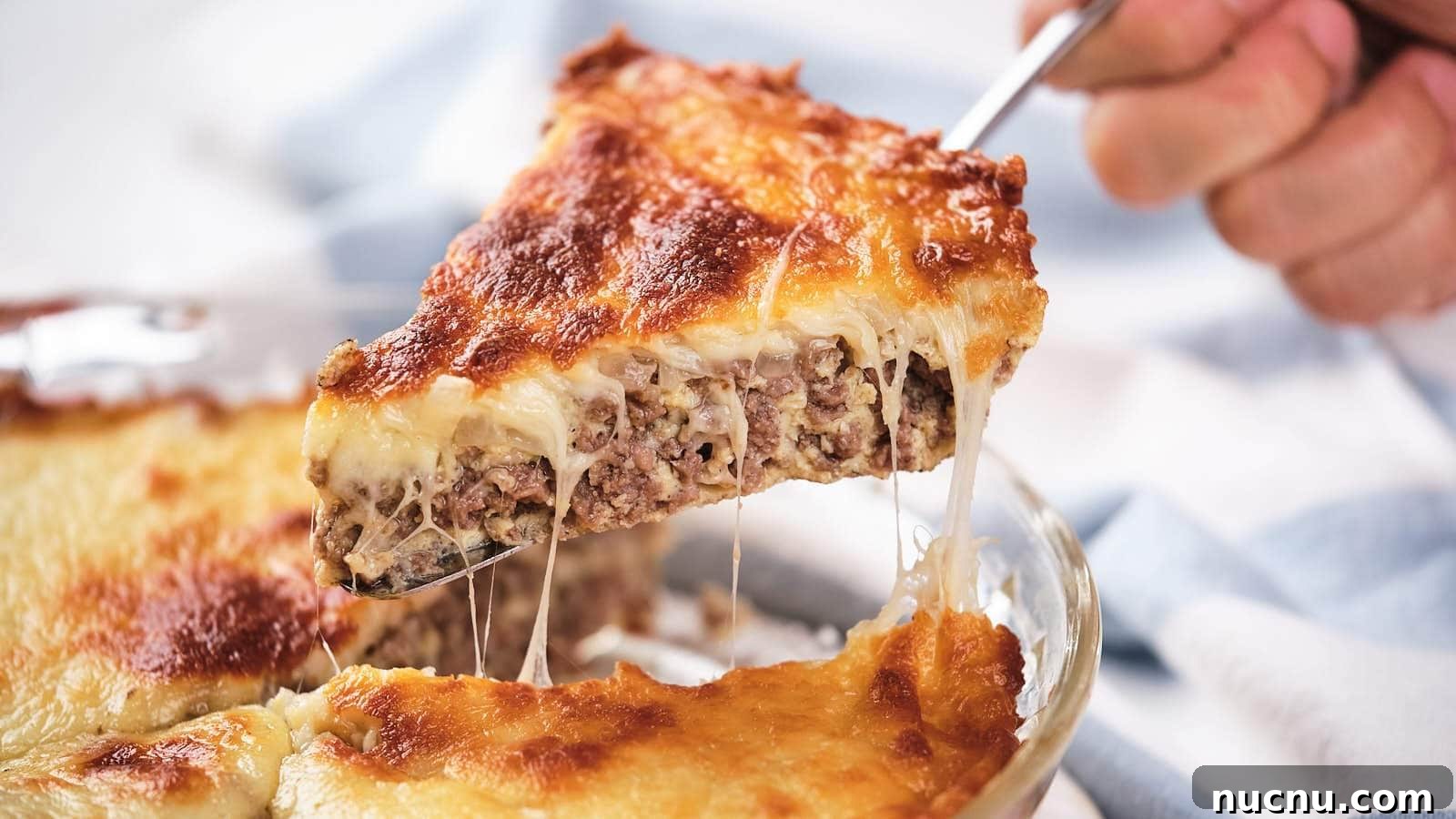 A slice of cheeseburger pie being lifted, showing layers of meat and melted cheese.