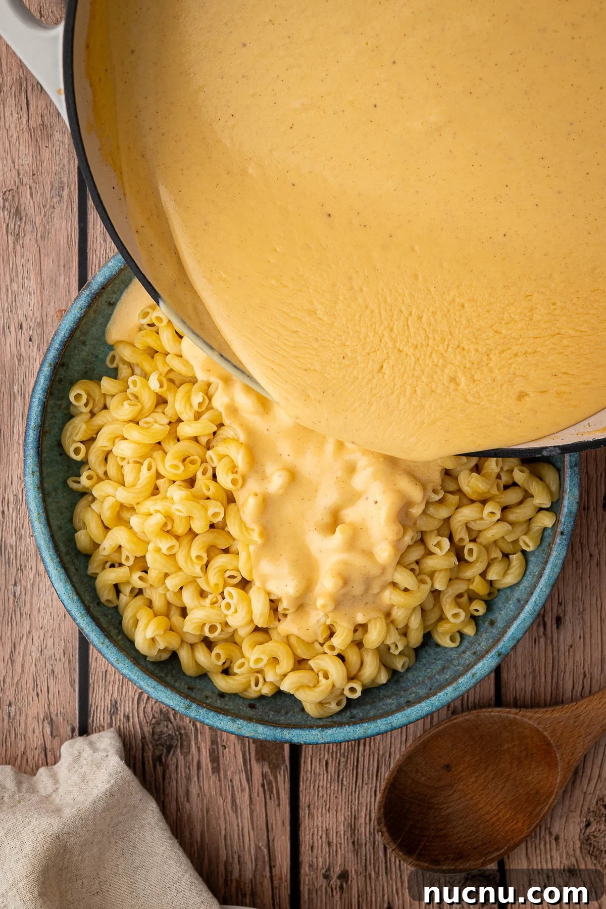 Creamy Stovetop Monterey Jack Mac and Cheese Recipe 6 Pouring the cheesy sauce onto the cooked elbow macaroni pasta in a large bowl.