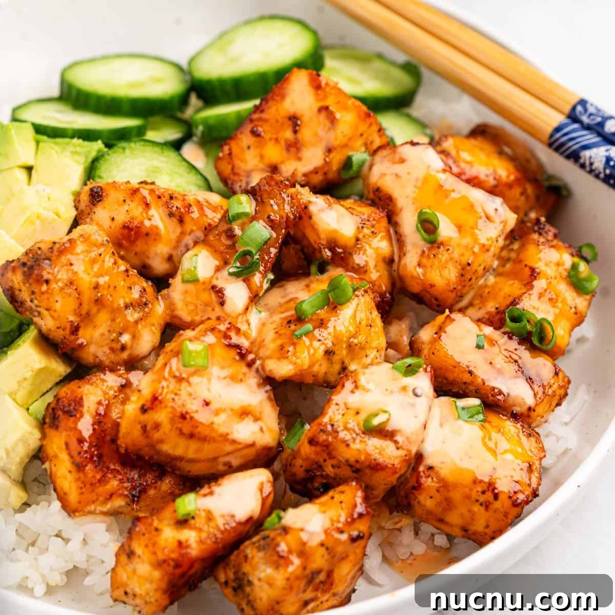 Crispy Air Fryer Salmon Bites with Lemon Garlic Dip 2 plate of air fryer salmon bites on bed of rice with slices of cucumbers and avocado.
