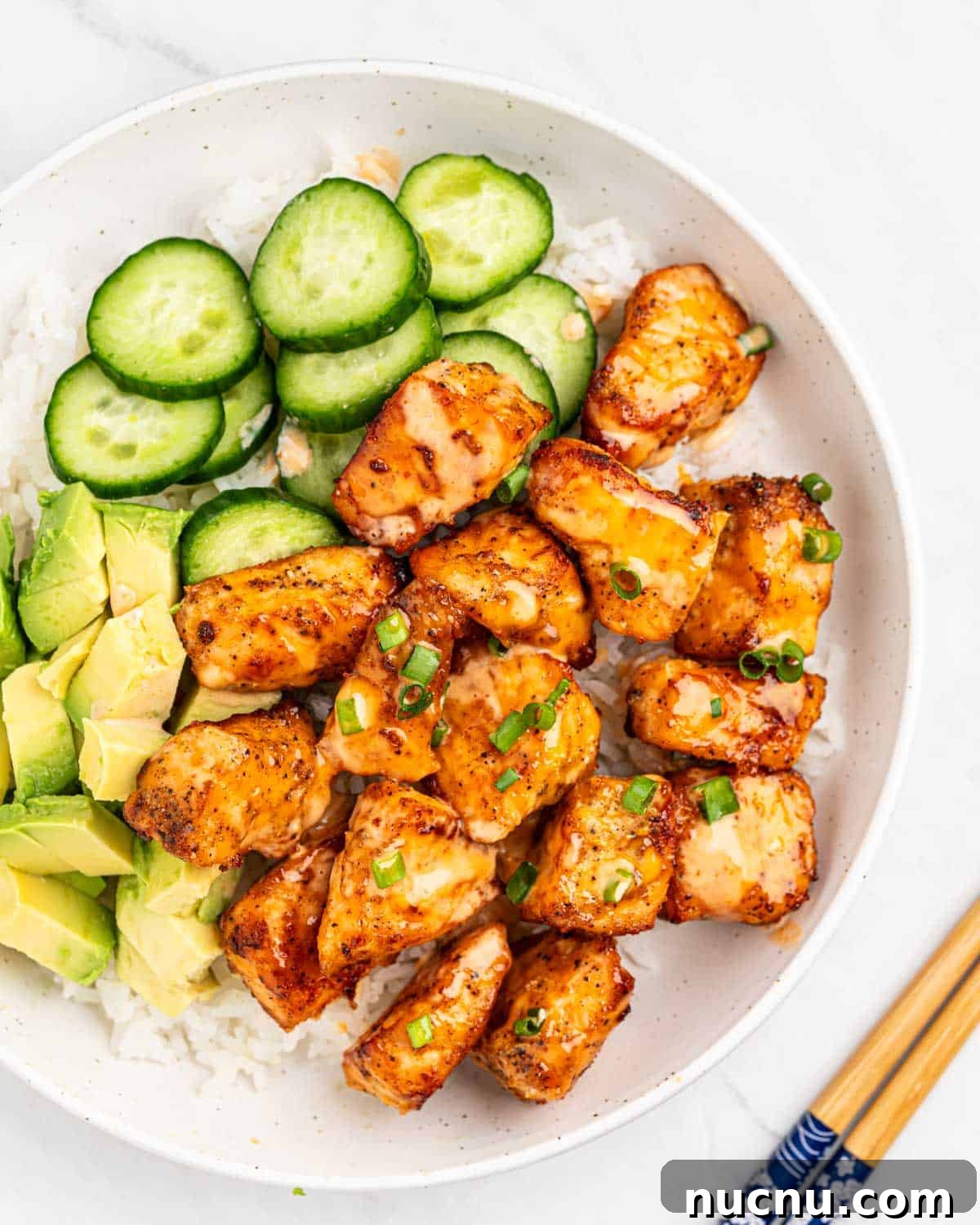 Crispy Air Fryer Salmon Bites with Lemon Garlic Dip 8 top down of plate of rice and air fryer salmon bites drizzled with sriracha mayo sauce.