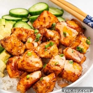 Crispy Air Fryer Salmon Bites with Lemon Garlic Dip 10 plate of air fryer salmon bites on bed of rice with slices of cucumbers and avocado.