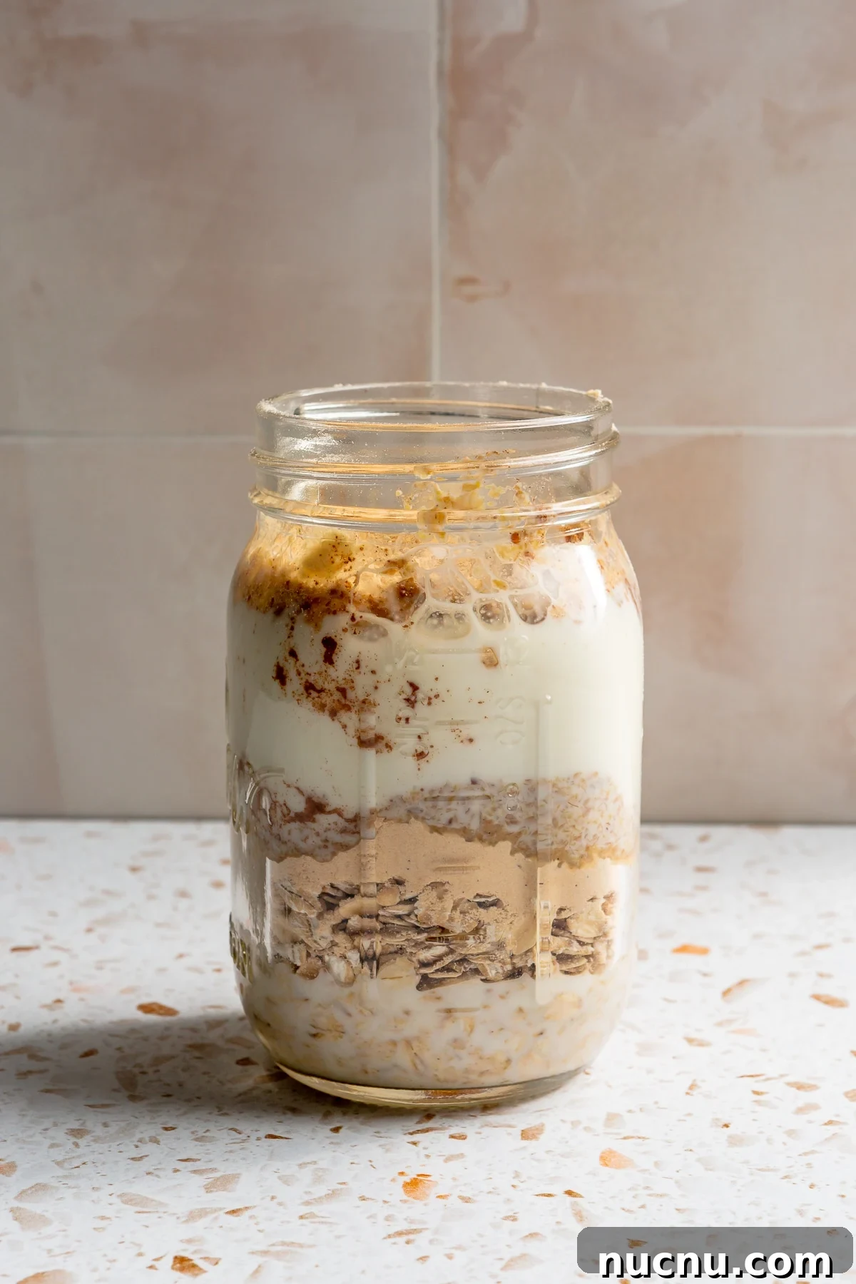 Ingredients for high protein overnight oats have been added to a mason jar.