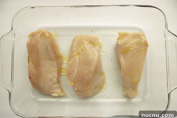 Juicy Air Fryer Chicken Breasts: Quick Crispy Recipe in 20 Minutes 8 Oil drizzled on raw chicken breats in a clear baking dish