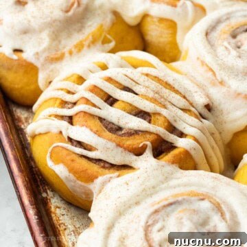 Pumpkin Spice Cinnamon Rolls: Soft, Fluffy Fall Recipe 17 Baked frosted pumpkin cinnamon rolls in metal pan.