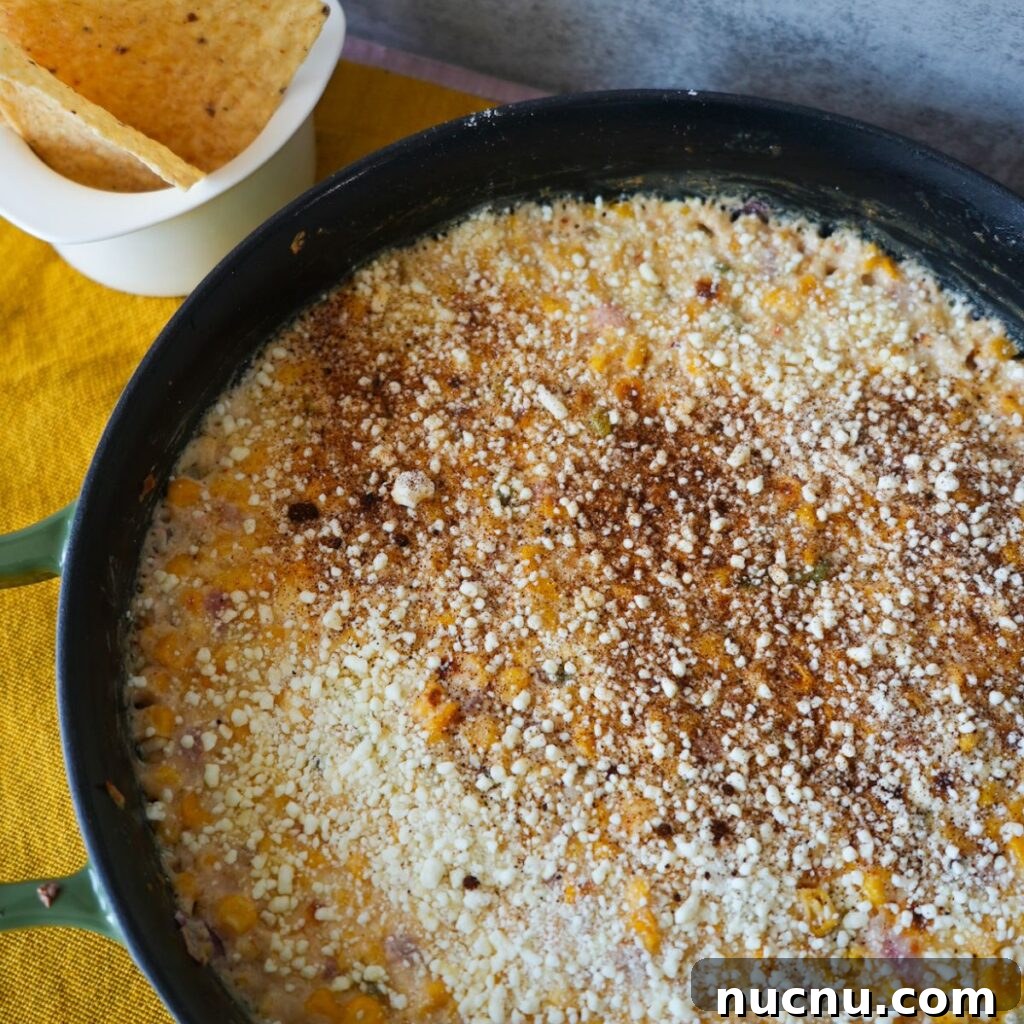 Mexican Street Corn Dip (Elote Dip Recipe + Video) 2 Elote dip recipe inside a cast iron skillet with chips on the side.
