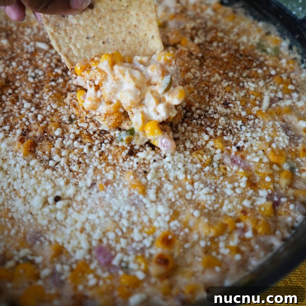 Mexican Street Corn Dip (Elote Dip Recipe + Video) 3 Elote dip being scooped out of the pan.