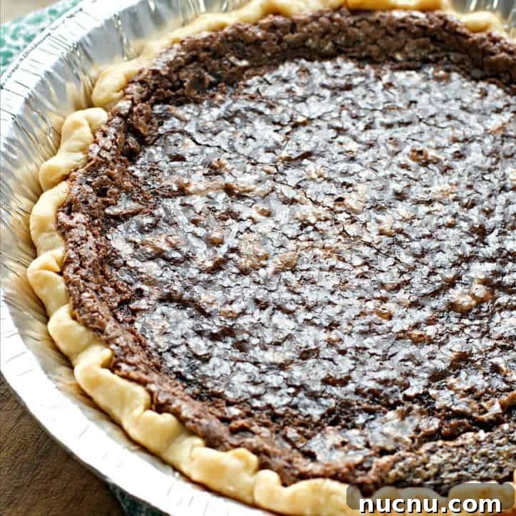 A 45 degree angle shot of the pie showing the shiny upper crust, tin pan and green napkin