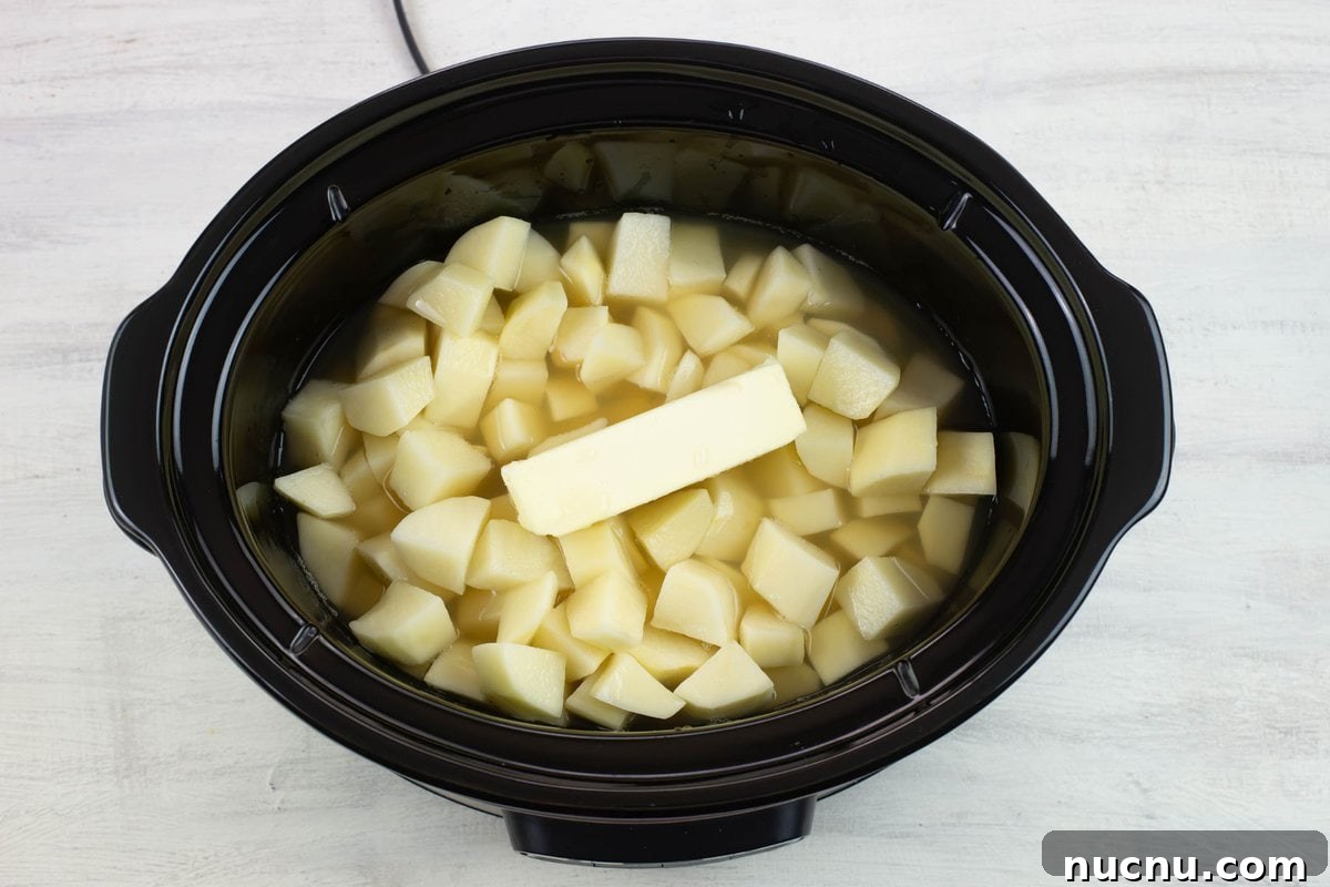 Million-Dollar Slow Cooker Mashed Potatoes Recipe 4 Adding the potatoes, chicken broth and butter in the slow cooker.