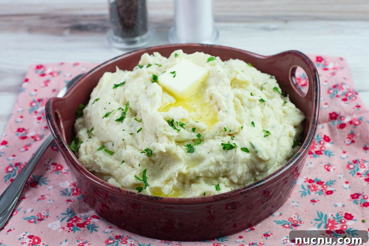 Million-Dollar Slow Cooker Mashed Potatoes Recipe 7 Serving bowl on a napkin filled with mashed potatoes.