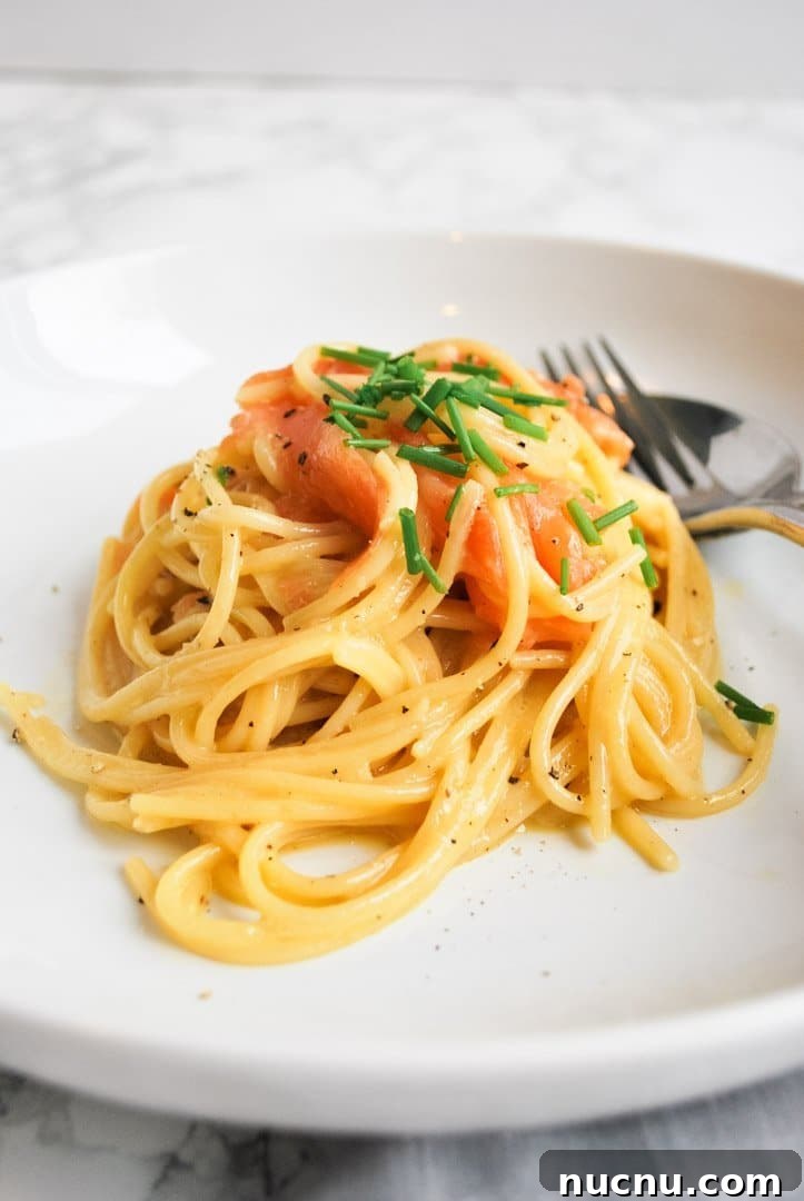Creamy Smoked Salmon Carbonara Recipe for Quick Weeknight Dinners 5 A white plate with a portion of smoked salmon carbonara in the middle of it.