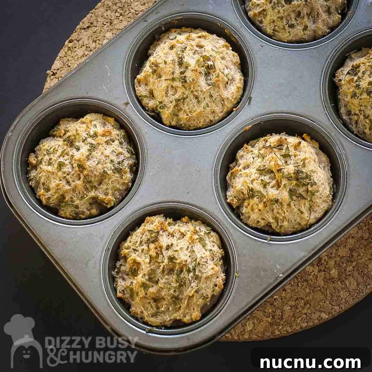 Overhead shot of biscuits in a metal muffin tin on a cork trivet.