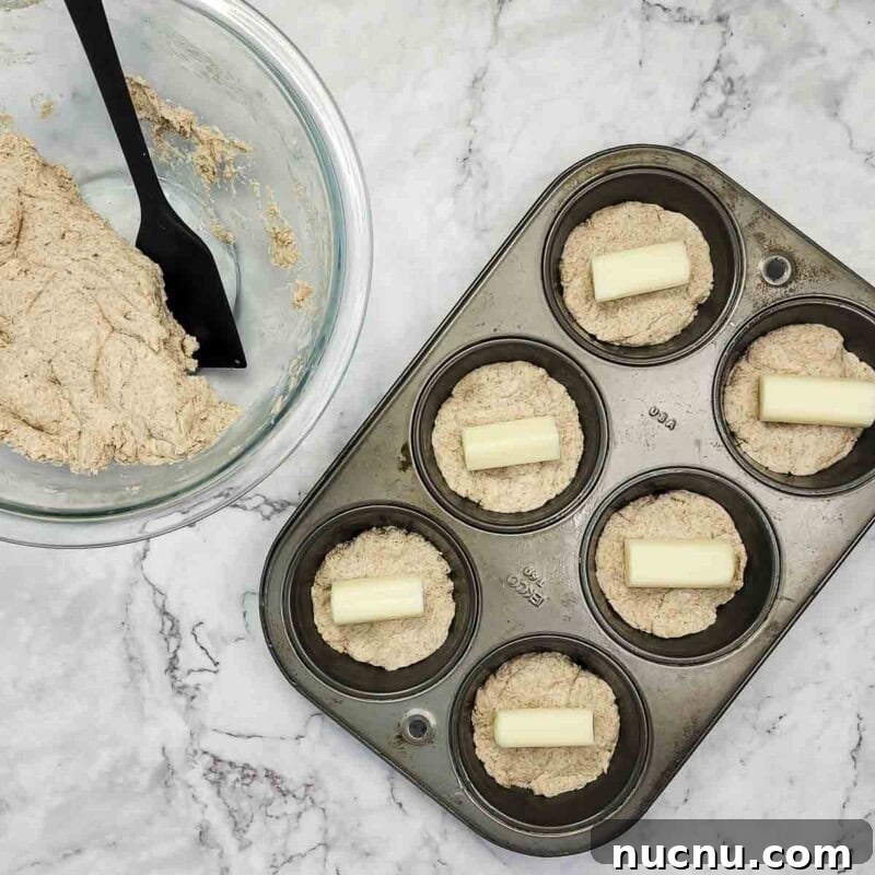 Distribute half the dough among muffin cups and add a piece of mozzarella.