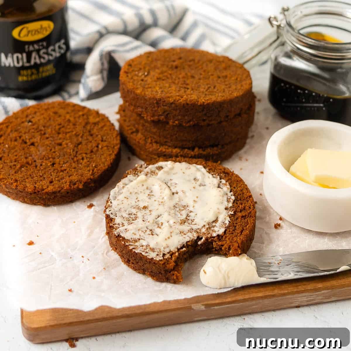 Authentic Boston Brown Bread Recipe: Steamed New England Classic 19 Sliced brown bread with one piece spread with butter, a bite taken out, and jars of molasses and butter on a wooden board.