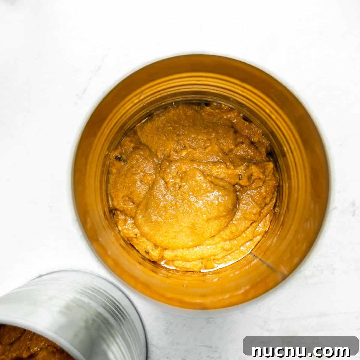 Authentic Boston Brown Bread Recipe: Steamed New England Classic 10 Open can viewed from above, containing dense, orange-brown pumpkin puree with a smooth, slightly textured surface. Another can is partially visible on the side.