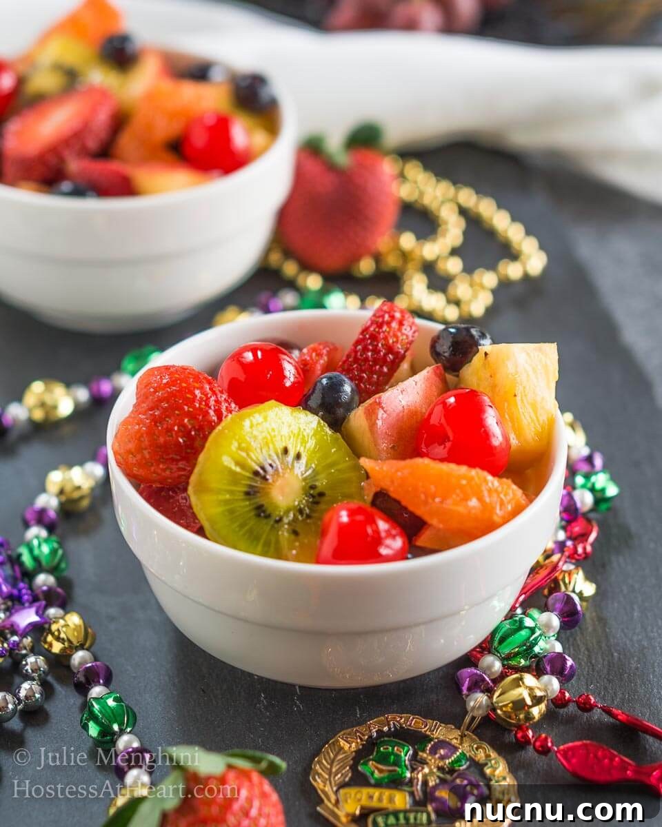 Boozy Mardi Gras Fruit Salad Recipe for Festive Parties 3 A two bowls fruit salad infused with Hurricane cocktail mix over gray slate and surrounded with Mardi Gras beads.
