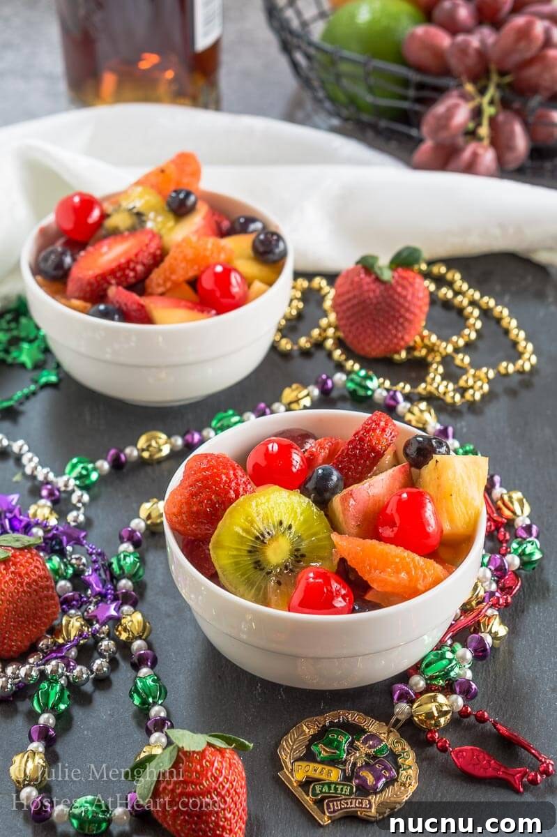 Boozy Mardi Gras Fruit Salad Recipe for Festive Parties 4 A two bowls fruit salad infused with Hurricane cocktail mix over gray slate and surrounded with Mardi Gras beads.