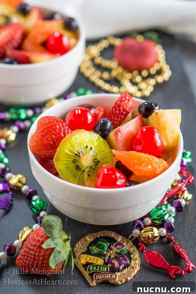 Boozy Mardi Gras Fruit Salad Recipe for Festive Parties 5 A bowl of Hurricane infused fresh fruit sitting on black slate and surrounded with Mardi Gras beads.